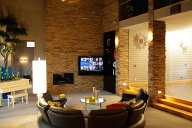 他の地域にあるトランジショナルスタイルのおしゃれなファミリールーム (ベージュの壁、カーペット敷き、標準型暖炉、石材の暖炉まわり、壁掛け型テレビ) の写真