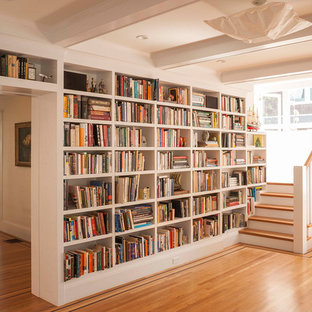Diseño de sala de estar con biblioteca abierta, de estilo americano, grande, sin chimenea, con paredes blancas y suelo de madera clara