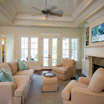 Elegant open concept dark wood floor family room photo in New Orleans with beige walls, a standard fireplace and a wall-mounted tv