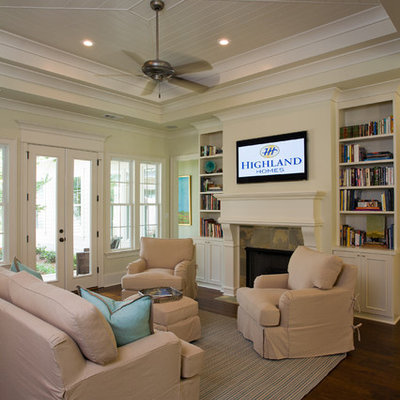 Family room - traditional open concept dark wood floor family room idea in New Orleans with beige walls, a standard fireplace and a wall-mounted tv