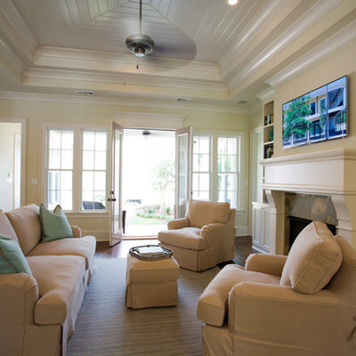 Family room - traditional open concept dark wood floor family room idea in New Orleans with beige walls, a standard fireplace and a wall-mounted tv