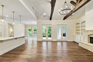 Example of a transitional medium tone wood floor and brown floor family room design in New Orleans with white walls, a standard fireplace and a brick fireplace