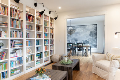Imagen de sala de estar con biblioteca cerrada tradicional renovada con paredes blancas, suelo de madera en tonos medios y suelo marrón