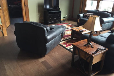 Diseño de sala de estar de estilo americano de tamaño medio con paredes verdes, suelo de madera en tonos medios, televisor independiente y suelo marrón