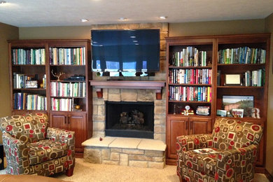 Diseño de sala de estar con biblioteca abierta contemporánea grande con paredes beige, moqueta, todas las chimeneas, marco de chimenea de piedra y televisor colgado en la pared