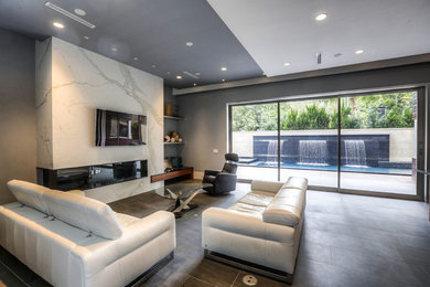 Example of a huge minimalist open concept slate floor and gray floor family room design in Houston with gray walls, a ribbon fireplace, a tile fireplace and a wall-mounted tv