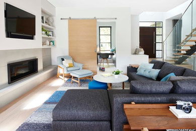 Diseño de sala de estar contemporánea con paredes blancas, suelo de madera clara, chimenea lineal, marco de chimenea de hormigón y pared multimedia