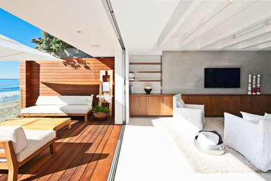 Imagen de sala de estar abierta moderna de tamaño medio sin chimenea con paredes blancas, suelo de cemento, televisor colgado en la pared y suelo gris