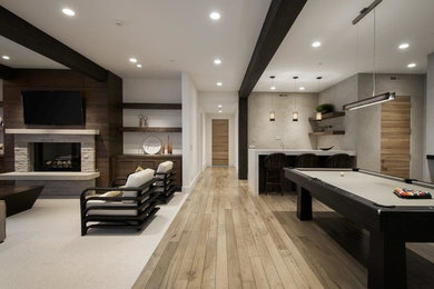 Example of a large trendy open concept medium tone wood floor game room design in Salt Lake City with white walls, a standard fireplace, a stone fireplace and a wall-mounted tv