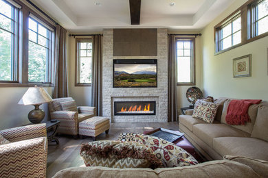 Cette image montre une salle de séjour traditionnelle de taille moyenne et ouverte avec un téléviseur fixé au mur, un mur beige, une cheminée standard et un manteau de cheminée en pierre.