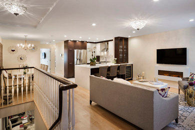 This is an example of a medium sized classic open plan games room in New York with beige walls, light hardwood flooring, a wall mounted tv, a ribbon fireplace and a plastered fireplace surround.