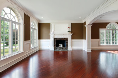 Wohnzimmer mit braunem Holzboden, Kamin, verputzter Kaminumrandung und rotem Boden in Atlanta