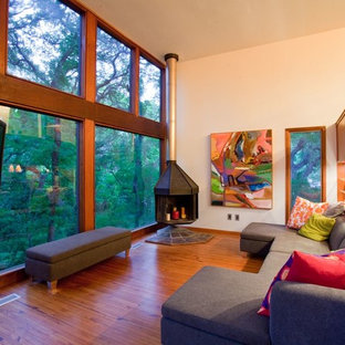 Modernes Wohnzimmer mit beiger Wandfarbe, braunem Holzboden, Eckkamin und Eck-TV in Austin