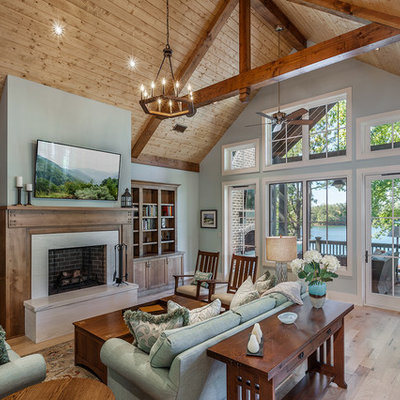 Example of a mountain style open concept light wood floor and beige floor family room library design in Other with a wall-mounted tv, a ribbon fireplace and green walls