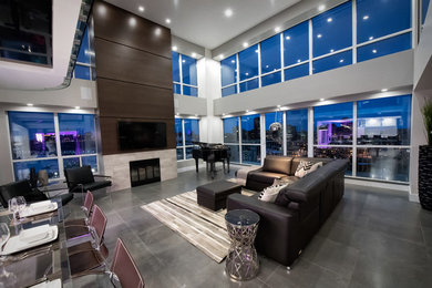 This is an example of a medium sized contemporary open plan games room in Ottawa with grey walls, concrete flooring, a ribbon fireplace, a tiled fireplace surround, a wall mounted tv and grey floors.