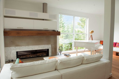 Modelo de sala de estar con rincón musical abierta contemporánea grande con paredes blancas, suelo de madera en tonos medios, todas las chimeneas y marco de chimenea de hormigón