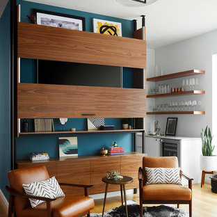 Modelo de sala de estar abierta, contemporánea, grande, sin chimenea, con suelo de madera clara y televisor retractable