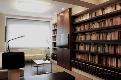 Modelo de sala de estar con biblioteca cerrada actual de tamaño medio sin chimenea y televisor con paredes beige y suelo de madera en tonos medios