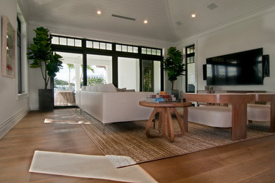 Large trendy open concept medium tone wood floor and brown floor family room photo in Miami with white walls and a wall-mounted tv