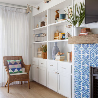 Mittelgroßes, Abgetrenntes Maritimes Wohnzimmer mit weißer Wandfarbe, Kamin, gefliester Kaminumrandung, hellem Holzboden und Wand-TV in Jacksonville