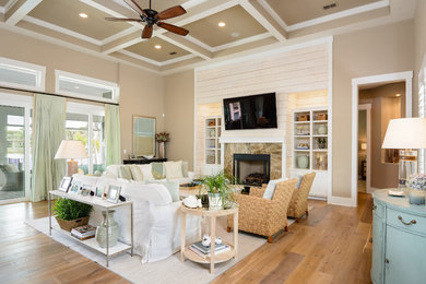 Large beach style open concept medium tone wood floor and brown floor family room photo in Jacksonville with beige walls, a standard fireplace, a stone fireplace and a wall-mounted tv