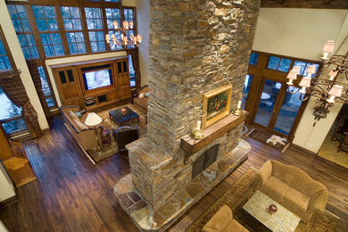 Inspiration for a rustic family room remodel in Other with a two-sided fireplace and a stone fireplace