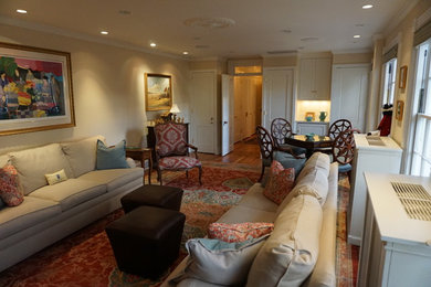 Diseño de sala de estar cerrada tradicional de tamaño medio con paredes beige, suelo de madera oscura y televisor retractable