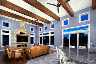 Diseño de sala de estar cerrada marinera grande con paredes azules, suelo de madera oscura, chimenea lineal, marco de chimenea de piedra y televisor colgado en la pared