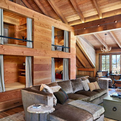 Mid-sized mountain style medium tone wood floor family room photo in Denver with brown walls, a standard fireplace, a stone fireplace and a media wall