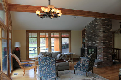 Ejemplo de sala de estar moderna con paredes beige, suelo de madera en tonos medios, todas las chimeneas y marco de chimenea de ladrillo