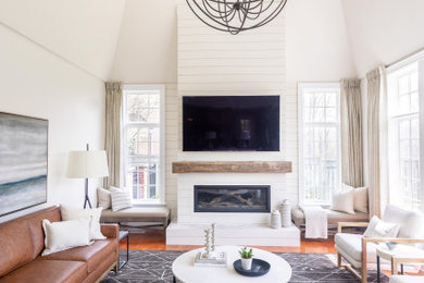 Example of a large transitional open concept medium tone wood floor and orange floor family room design in Toronto with beige walls, a standard fireplace, a wood fireplace surround and a wall-mounted tv
