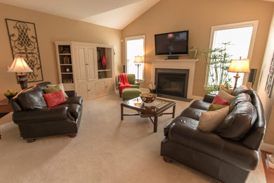 Modelo de sala de estar abierta clásica grande con paredes beige, moqueta, todas las chimeneas, marco de chimenea de yeso y televisor colgado en la pared