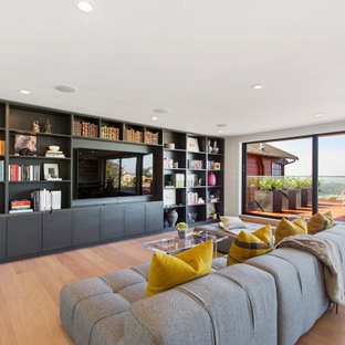 Family room library - large contemporary open concept light wood floor and beige floor family room library idea in San Francisco with white walls and a wall-mounted tv