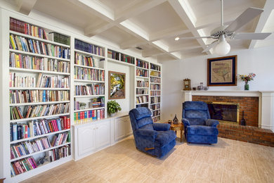 Imagen de sala de estar con biblioteca abierta clásica renovada de tamaño medio sin televisor con paredes blancas, suelo de baldosas de cerámica, todas las chimeneas, marco de chimenea de ladrillo y suelo beige