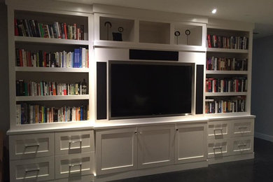 Imagen de sala de estar con biblioteca cerrada clásica renovada de tamaño medio sin chimenea con paredes blancas, suelo de madera oscura, pared multimedia y suelo negro