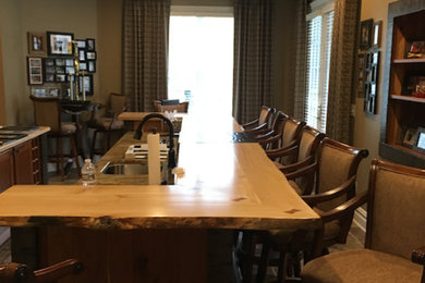 Example of a mid-sized classic enclosed laminate floor and brown floor family room design in Other with a bar, beige walls, no fireplace and a tv stand