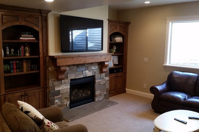 Modelo de sala de estar abierta clásica de tamaño medio con paredes beige, moqueta, todas las chimeneas, marco de chimenea de piedra y televisor colgado en la pared