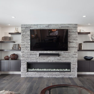 Inspiration for a mid-sized modern open concept dark wood floor game room remodel in Orange County with gray walls, a hanging fireplace, a stone fireplace and a media wall