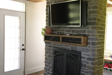 モントリオールにある中くらいなカントリー風のおしゃれなオープンリビング (濃色無垢フローリング、標準型暖炉、石材の暖炉まわり) の写真