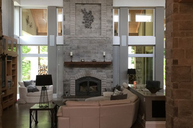 Aménagement d'une grande salle de séjour classique ouverte avec un mur beige, un sol en bois brun, une cheminée standard, un manteau de cheminée en pierre, un téléviseur encastré et un sol marron.
