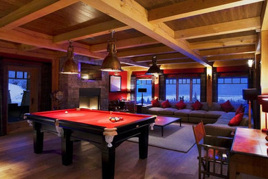 Game room - huge rustic open concept medium tone wood floor game room idea in Vancouver with red walls, a standard fireplace, a stone fireplace and a wall-mounted tv