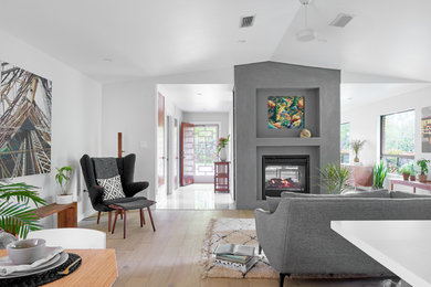 Foto de sala de estar contemporánea grande con paredes grises, suelo de madera clara, chimenea de doble cara, marco de chimenea de yeso y suelo beige