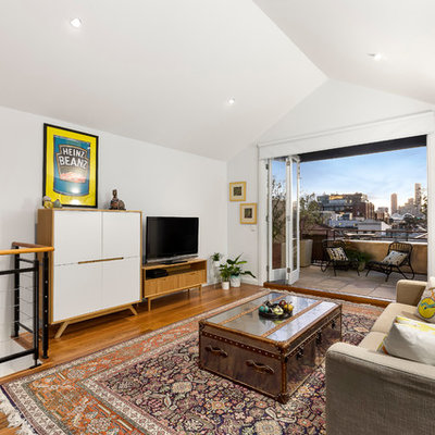 Example of a mid-sized trendy loft-style medium tone wood floor family room design in Melbourne with white walls, no fireplace and a tv stand