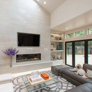 Example of a large minimalist travertine floor family room design in Houston with beige walls, a standard fireplace, a tile fireplace and a wall-mounted tv