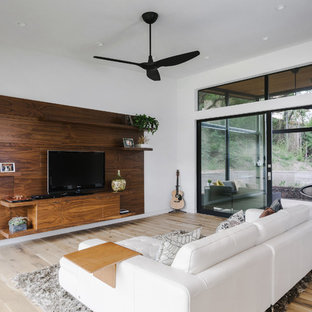Large minimalist open concept light wood floor and brown floor family room photo in Austin with white walls, no fireplace and a tv stand