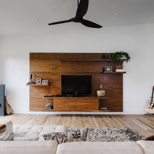 Cette image montre une grand salle de séjour minimaliste ouverte avec un mur blanc, un sol en bois clair, aucune cheminée, un téléviseur indépendant et un sol marron.