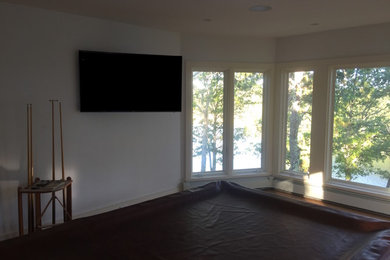 Foto de sala de juegos en casa abierta tradicional de tamaño medio con paredes blancas, suelo de madera en tonos medios y televisor colgado en la pared