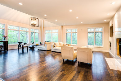 Example of a large trendy open concept dark wood floor and brown floor family room design in Milwaukee with white walls, a standard fireplace, a plaster fireplace and a wall-mounted tv