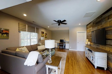 Inspiration for a large transitional enclosed medium tone wood floor and brown floor family room library remodel in Raleigh with gray walls and a wall-mounted tv