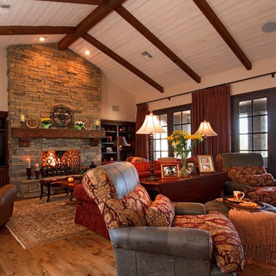 Family room - rustic open concept medium tone wood floor family room idea in Phoenix with beige walls, a standard fireplace, a stone fireplace and a media wall